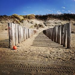 Wooden posts on beach against sky