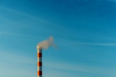 Close-up of smoke stack against blue sky