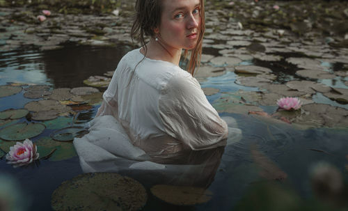 Young woman with arms raised in lake