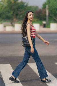 Young woman with sling bag crossing road