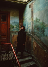 Full length of young man looking through window in building