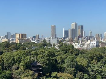 Trees and buildings against clear sky