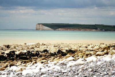 View of calm beach against cloudy sky