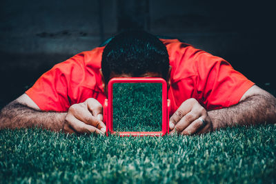 Man holding mirror with grass reflection