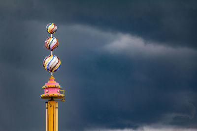 Low angle view of communications tower against cloudy sky