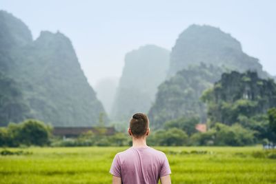 Rear view of man looking at mountains against sky