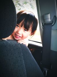 Smiling girl sitting behind seat in car