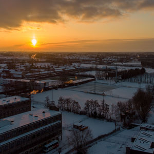 High angle view of snow covered buildings against sky during sunset