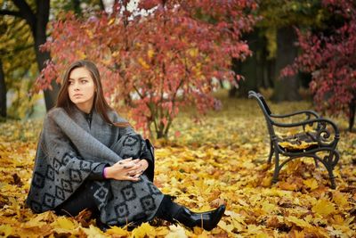 Portrait of woman sitting in park during autumn