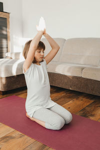 The girl sits on a sports mat and practices yoga. yoga for children and adults at home and online. 