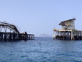 Pier over sea against clear blue sky