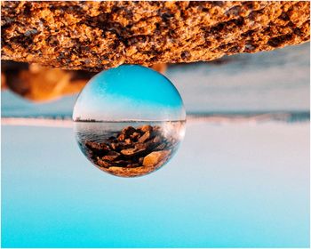 Close-up of crystal ball against blue sea