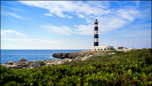 Lighthouse by sea against sky