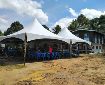 People walking by houses against sky