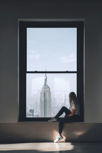 Side view of woman looking through window