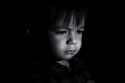 Portrait of cute boy against black background