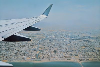 Aerial view of airplane flying over landscape against sky