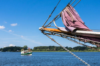 Boat sailing on river against blue sky