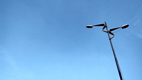 Low angle view of telephone pole against clear blue sky