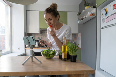 Smiling woman vlogging at kitchen