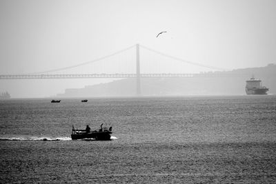 Boat in tagus river against 25 de abril bridge