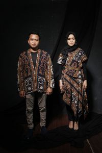 Portrait of young couple standing against wall