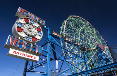 Low angle view of ferris wheel against blue sky