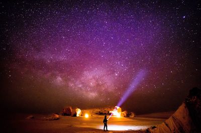 Woman standing against star field at night