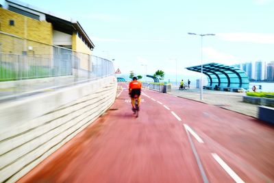 Rear view of man walking on road against sky