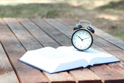 Close-up of clock with open book on table