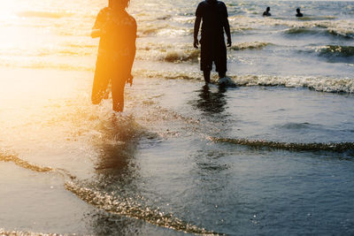 Rear view of women on beach during sunset