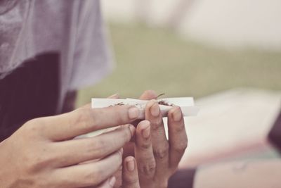 Midsection of man rolling marijuana joint