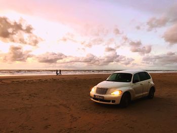 Vintage car on sand at beach against sky