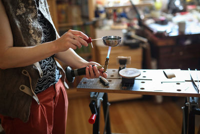 The master woman near the bench works with tools, on the torch boils water with a metal plate. 