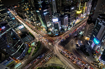 High angle view of traffic on road amidst illuminated buildings in city at night