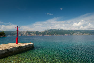 Lighthouse by sea against blue sky