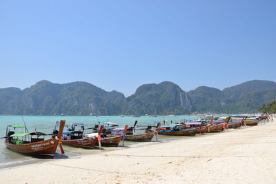 Boats moored on beach against clear blue sky