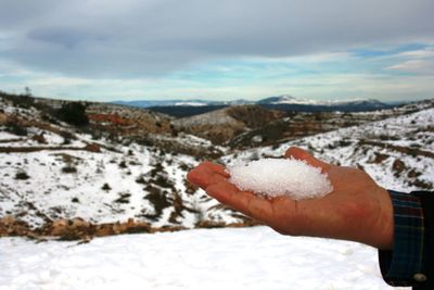Close-up of hand on snow covered landscape