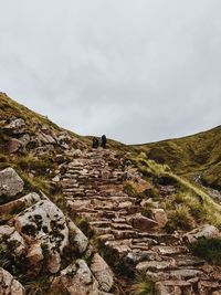 Rear view of people walking on mountain against sky