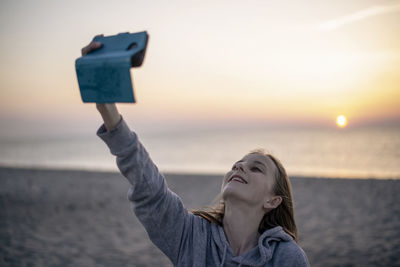 Portrait of woman on beach against sky during sunset