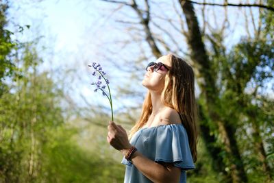 Woman wearing sunglasses standing against plants