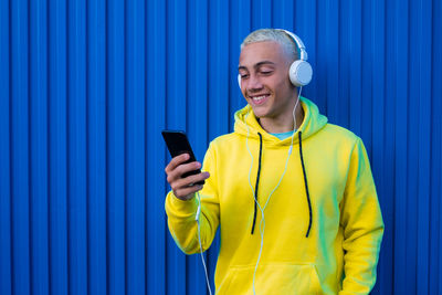 Young man with headphones against blue wall