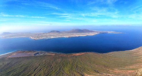 Aerial view of landscape and mountains against blue sky