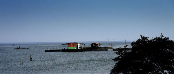 Huts on sea against clear sky