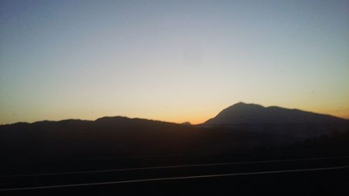 Silhouette landscape against clear sky during sunset