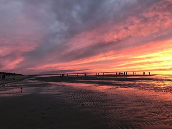 Scenic view of beach against dramatic sky during sunset