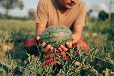 Close-up of man holding ice cream on field