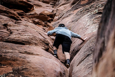 Full length of woman climbing rock formation