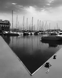 Sailboats moored at harbor against sky