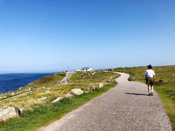 Rear view of man on sea shore against clear sky